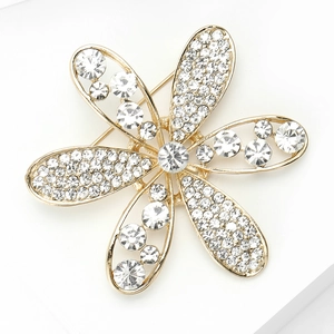 Détail d'une broche fleur dorée ornée de strass blancs brillants et étincelants