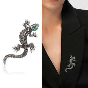 Macro detail of a crystal-studded lizard brooch on black blazer with silver reflections