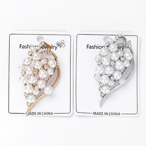 Detail of gold and silver alloy brooches with pearls and rhinestones on display card