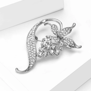 Close-up of silver floral brooch with white rhinestones on a white geometric stand