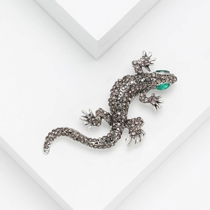 Macro detail of silver lizard brooch with brown rhinestones and green gemstone head