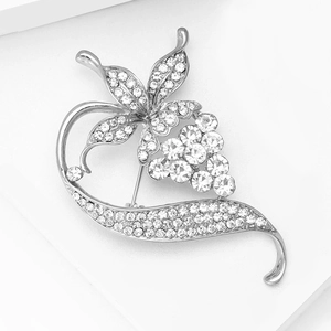 Detailed close-up of a silver vine brooch with sparkling rhinestones on a white stand