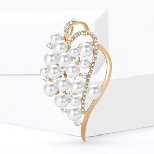 Elegant gold heart brooch with white pearls and sparkling rhinestones on white backdrop