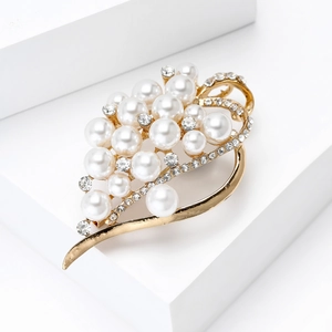 Detailed close-up of a luxury gold brooch with white pearls and sparkling rhinestones