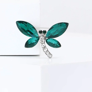 Broche libellule exquise avec ailes en cristal vert sur podium géométrique blanc
