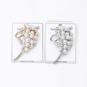 Close-up of gold and silver fruit-shaped brooches with pearls and crystals on display cards