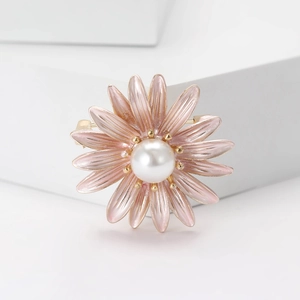 Elegant pink enamel daisy brooch with a glossy white pearl center on a white pedestal