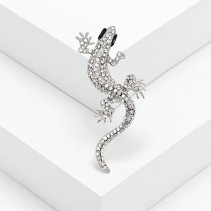 Macro shot of silver gecko brooch with sparkling white and iridescent rhinestones