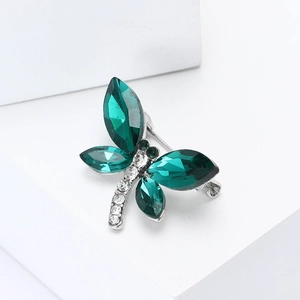 Broche libellule élégante en cristal émeraude sur fond blanc épuré et minimaliste