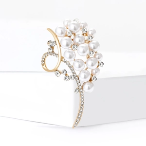 Elegant gold floral brooch with white pearls and sparkling rhinestones on white display
