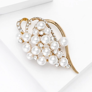 Close-up of golden leaf brooch featuring elegant white pearls and sparkling crystals