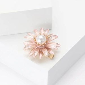 Elegant daisy flower brooch with pink enamel petals and a pearl center on white blocks