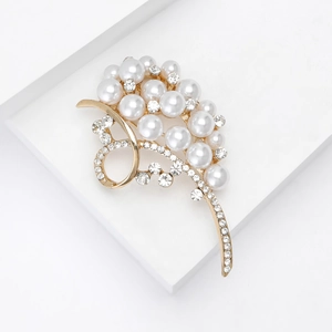 Close-up of golden floral brooch with white pearls and sparkling crystal rhinestones