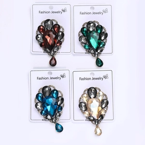Detail view of four vintage teardrop crystal brooches in emerald, ruby, blue and gold colors