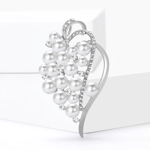Elegant silver heart-shaped pearl brooch with sparkling rhinestones on white pedestal