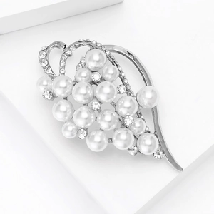 Macro detail of elegant silver-toned brooch with pearls and rhinestones on geometric base