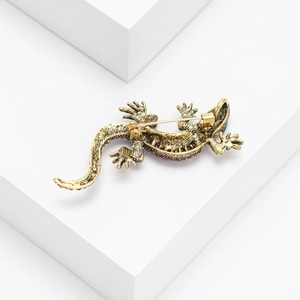 Close-up of alloy lizard brooch featuring red and green rhinestones and safety pin back