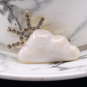 Close-up of cloud and sun brooch with white marble drip oil and grey rhinestones