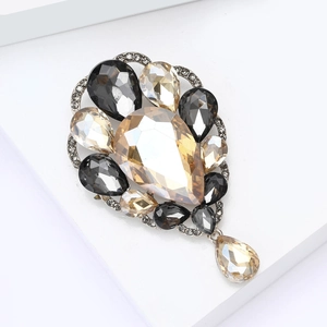 Detailed close-up of a champagne water-drop brooch with crystals and hanging pendant