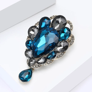Detailed macro view of vintage silver brooch with deep blue crystals and teardrop pendant
