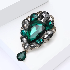 Detail of vintage glass brooch with emerald green and smoke grey gemstones on gold base