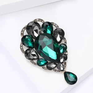 Macro shot of vintage brooch with deep green pear-cut gemstones and silver micro-pave crystals