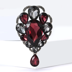 Detailed view of vintage brooch with deep red teardrop crystal and silver accents