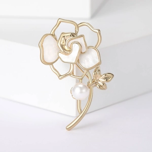 Vue détaillée de la broche camélia avec perle et feuille dorée sur blocs blancs
