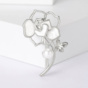 Détail macro d'une broche camélia avec pétales en nacre et une grande perle ronde blanche