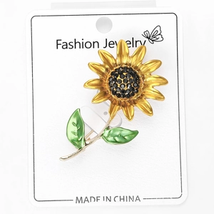 Détail de la broche tournesol aux pétales dorés et strass noirs sur carte de support