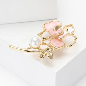 Détail de la broche camélia dorée avec pétales en émail rose et perle blanche ronde