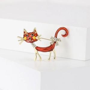 Detailed view of creative orange enamel cat brooch with rhinestones on a white stand