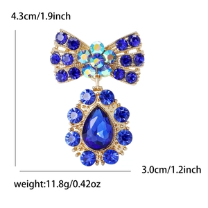 Broche nœud élégante dorée avec strass bleus et un pendentif en forme de poire