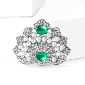 Broche couronne vintage de luxe avec pierres vertes et perles sur support blanc