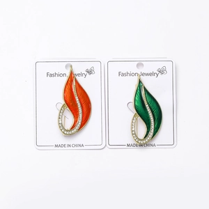 Detail of elegant enamel leaf brooches in orange and green with micro-inlaid rhinestones