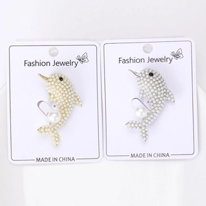 Detail showing gold and silver dolphin brooches with inlaid pearls on a display card