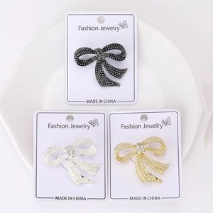 Detailed close-up of bow brooches in gold, silver, and black with pearls and rhinestones