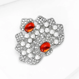Détail d'une broche fleur rétro avec perles, pierres rouges et cristaux pavés
