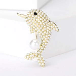 Detail of dolphin brooch with white faux pearls and gold plating on geometric stand