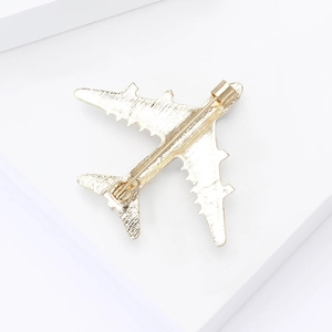 Detail view showing the back structure and sturdy metal pin clasp of the golden airplane brooch