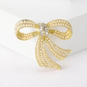 Detail of elegant gold-tone bow brooch with faux pearls and sparkling crystal center