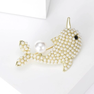 Detail of dolphin brooch with white pearls and gold alloy base in macro shot