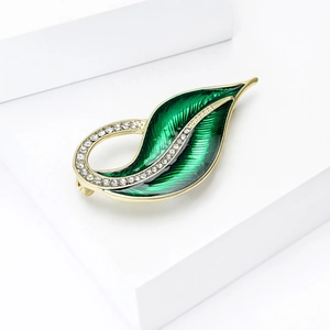 Detailed close-up of leaf brooch featuring green enamel finish and white rhinestone accents