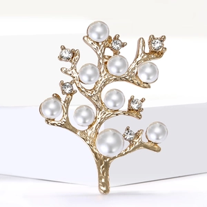 Gros plan sur la broche arbre dorée élégante avec perles blanches et strass brillants
