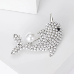 Detailed close-up of a silver dolphin brooch encrusted with white pearls and black gem eye