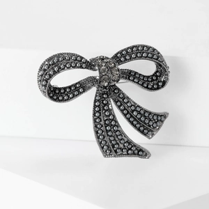 Detail of vintage bow brooch with grey pearls and rhinestones on a geometric stand