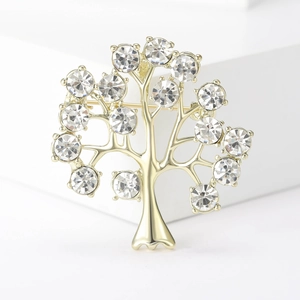 Broche arbre de vie dorée élégante ornée de cristaux brillants sur un support blanc
