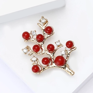 Vue détaillée de la broche branche dorée avec perles rouges et strass brillants de luxe