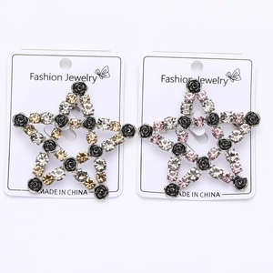 Detail view of pentagram brooches with black metal roses and shimmering crystals