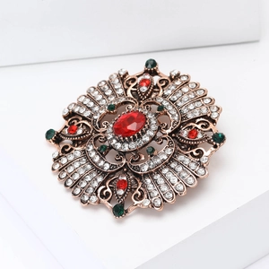 Close-up of vintage baroque brooch with central red gemstone and sparkling rhinestones